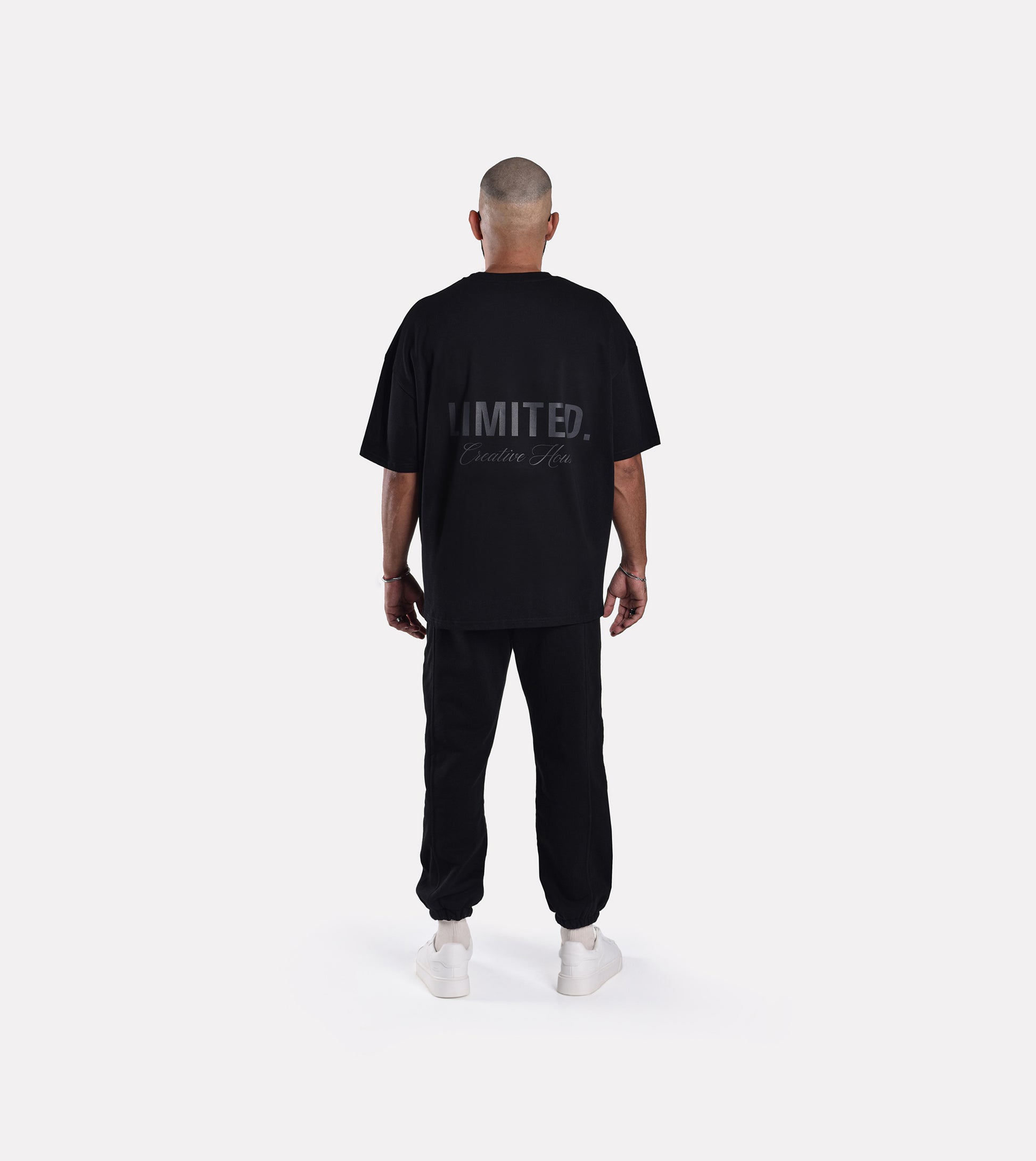 Back view of model wearing LIMITED. Oversized mens t-shirt in black with black LIMITED. branding on the back