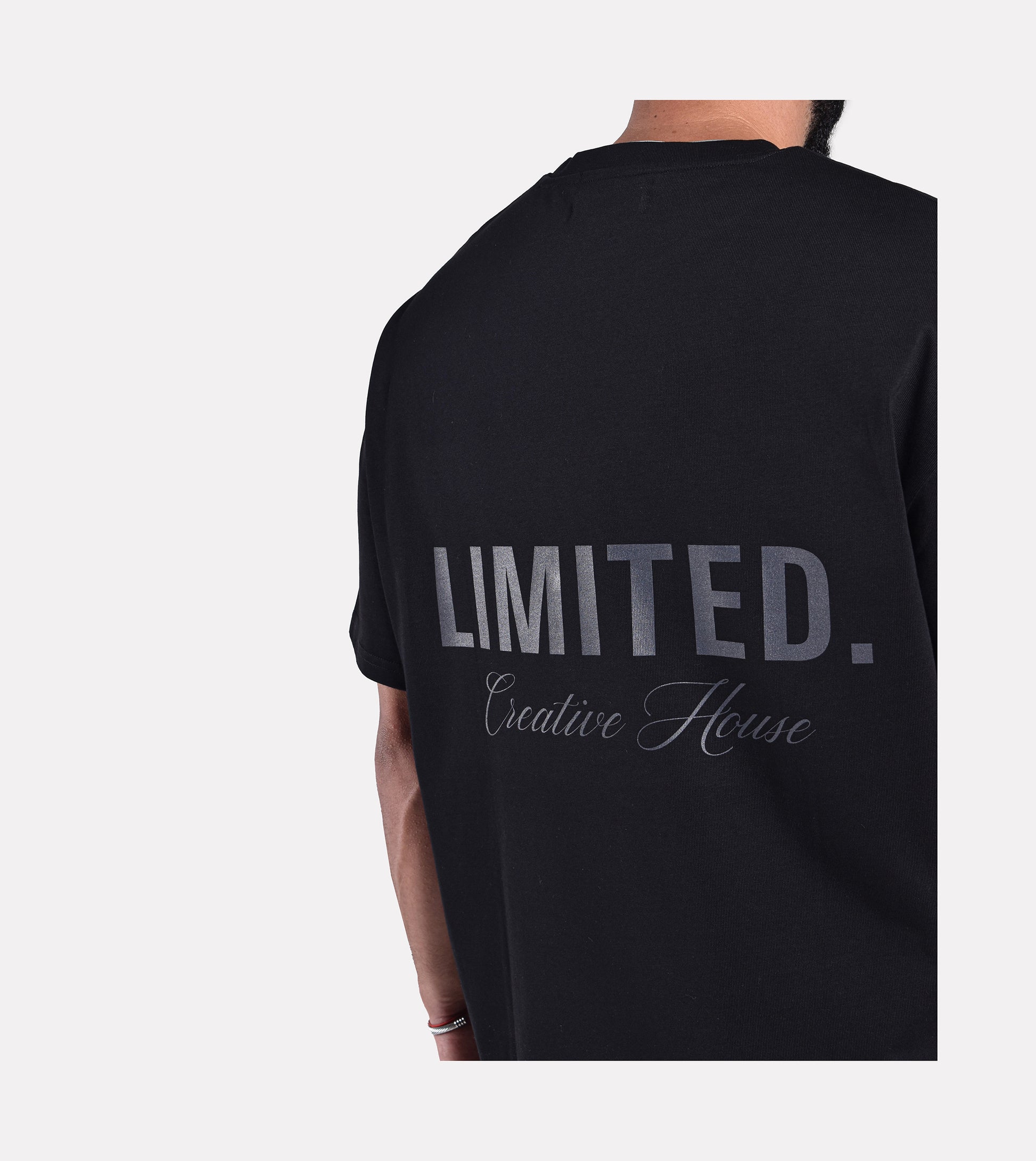 Close-up of model wearing LIMITED. Oversized mens t-shirt back view in black with black LIMITED. branding on the back.