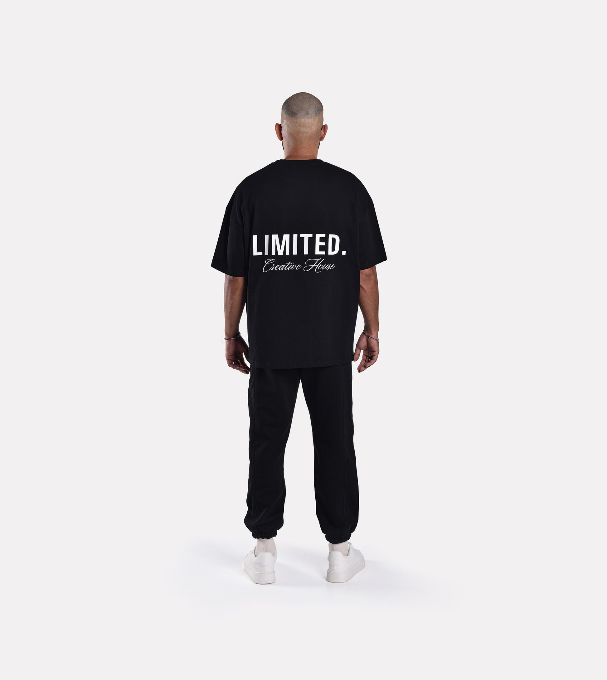 Back view of model wearing LIMITED. Oversized mens t-shirt in black with white big LIMITED. branding on the back