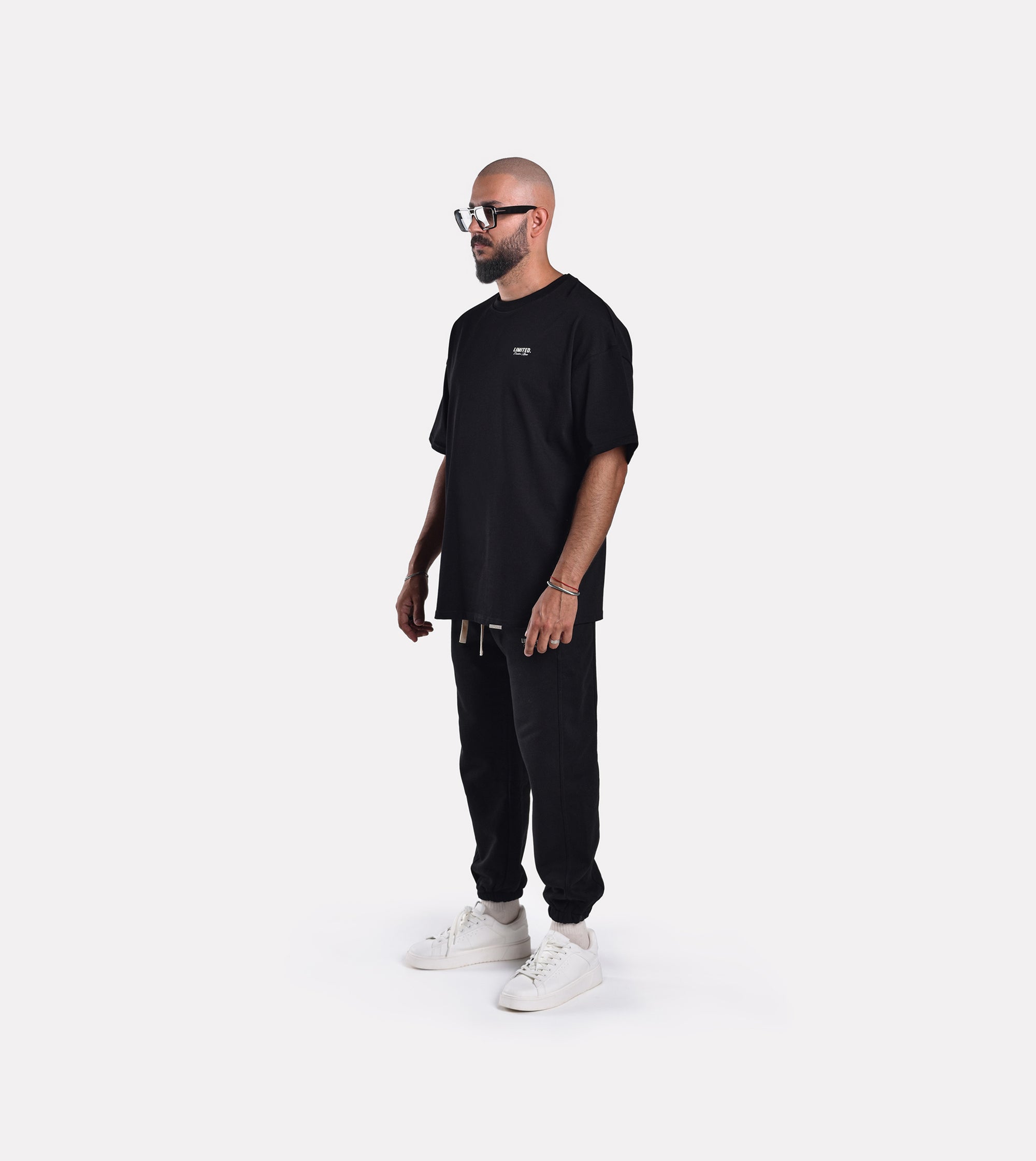 Side-view of model wearing LIMITED. Oversized mens t-shirt in black with small white branding on the left chest.