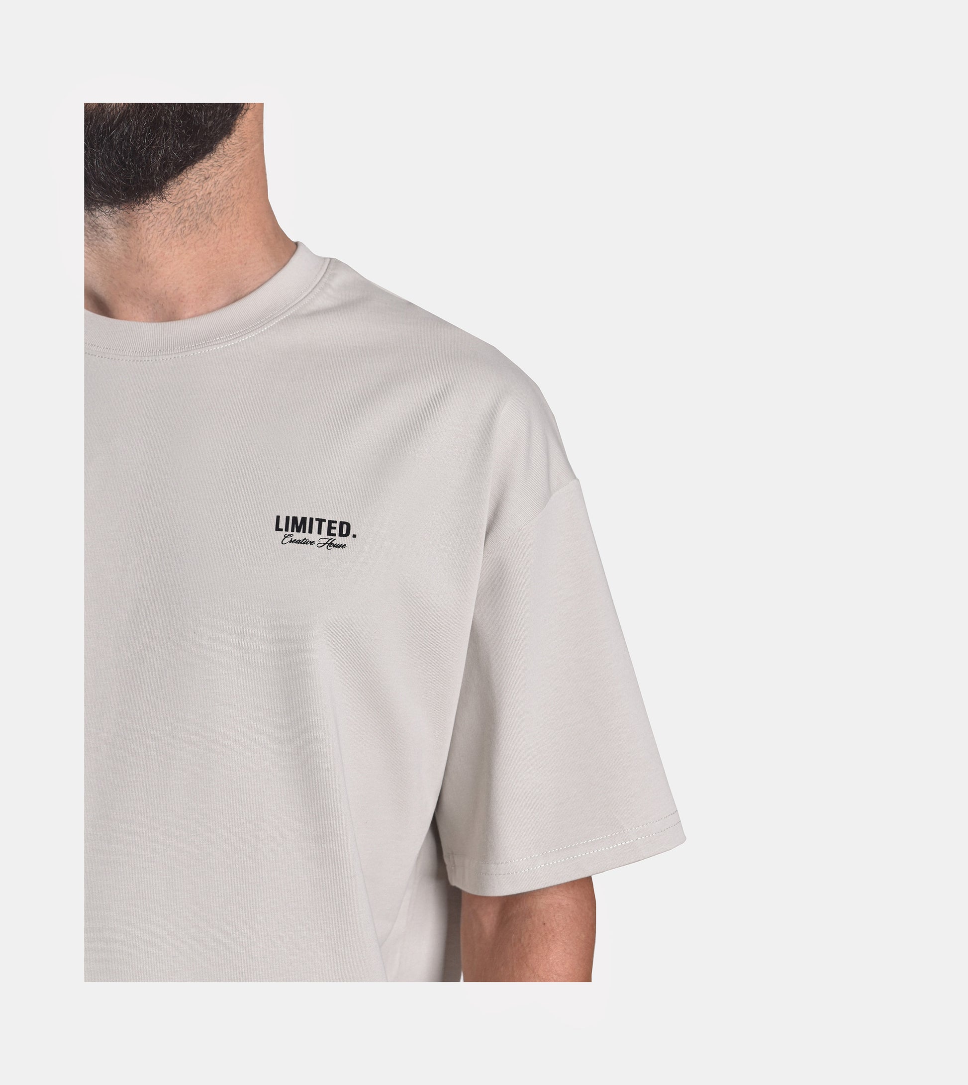 Close-up of model wearing LIMITED. Oversized mens t-shirt front view in whisper grey with black small branding on the left chest.