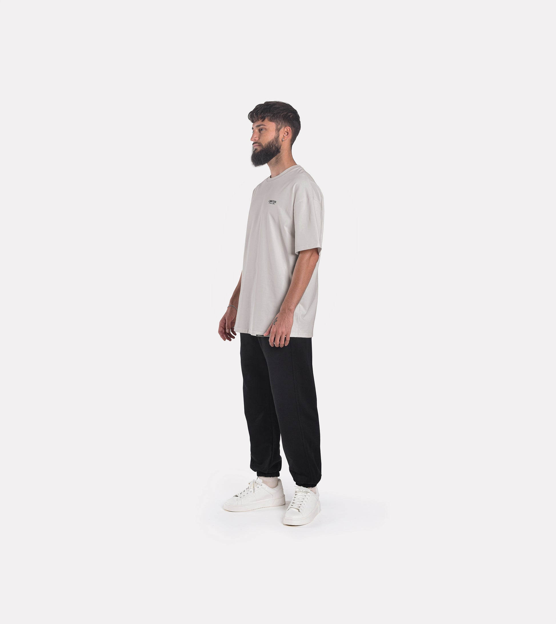 Side-view of model wearing LIMITED. Oversized mens t-shirt in whisper grey with small black branding on the left chest.