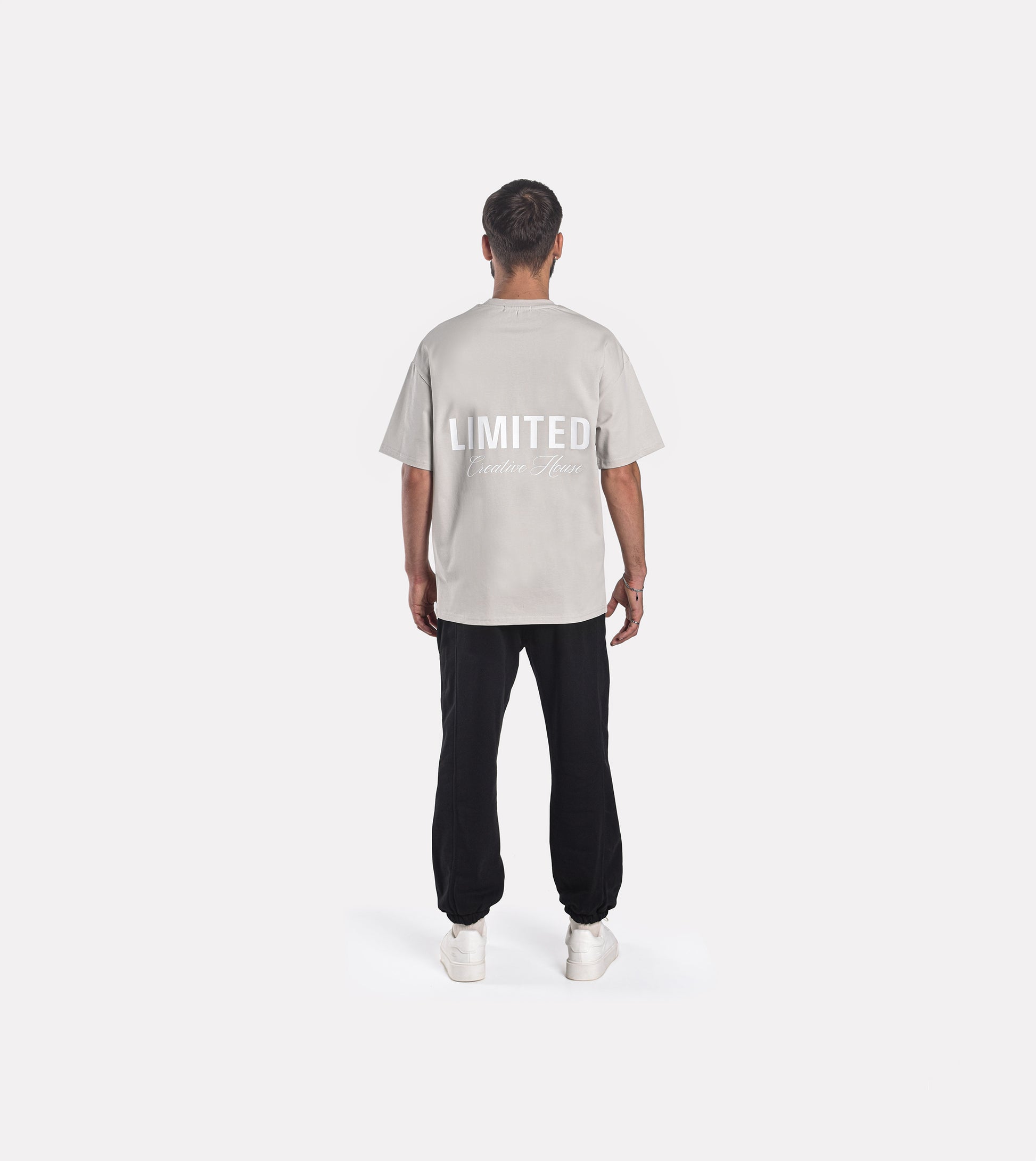 Back view of model wearing LIMITED. Oversized mens t-shirt in whisper-grey with white big LIMITED. branding on the back