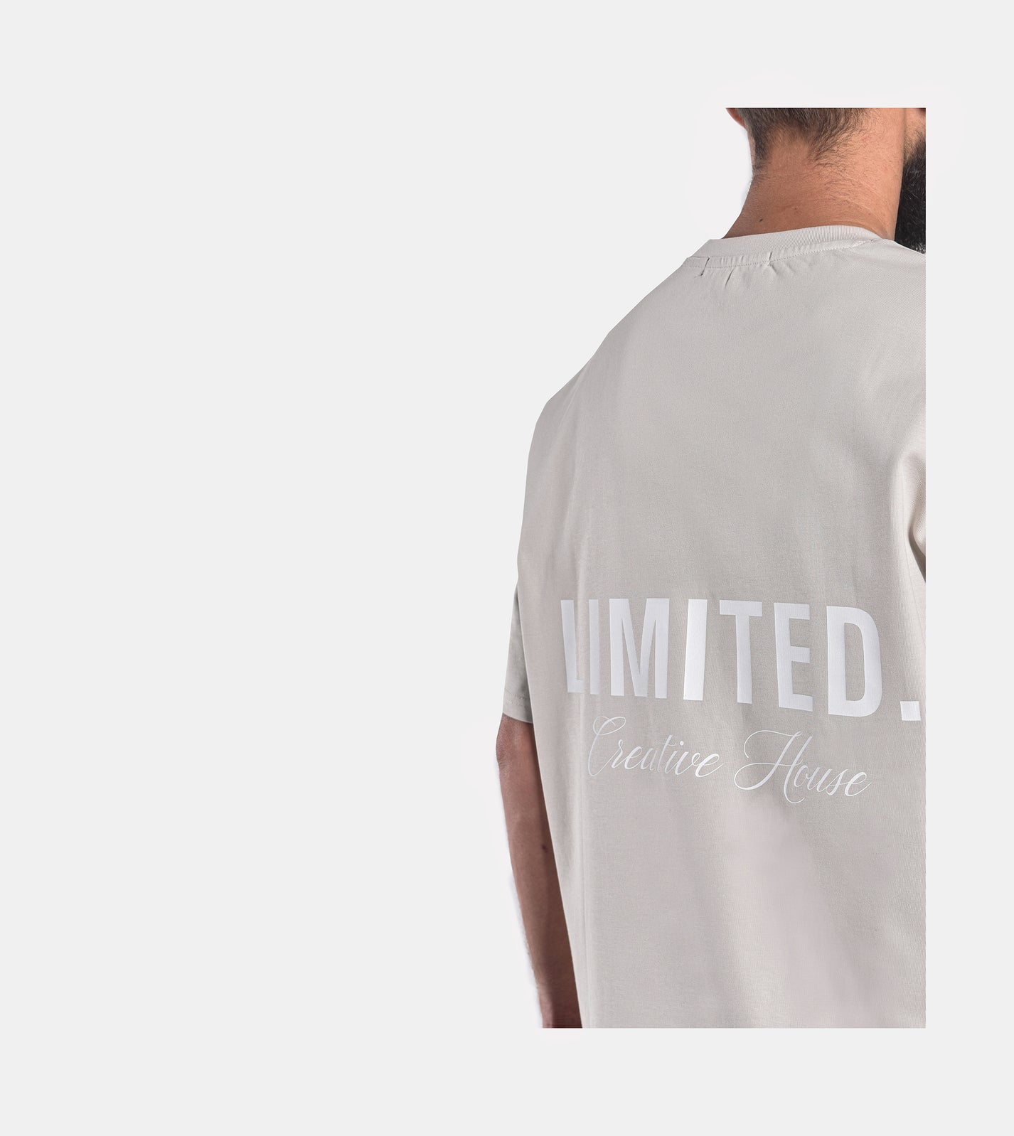 Close-up of model wearing LIMITED. Oversized mens t-shirt back view in whisper-grey with big white LIMITED. branding on the back.
