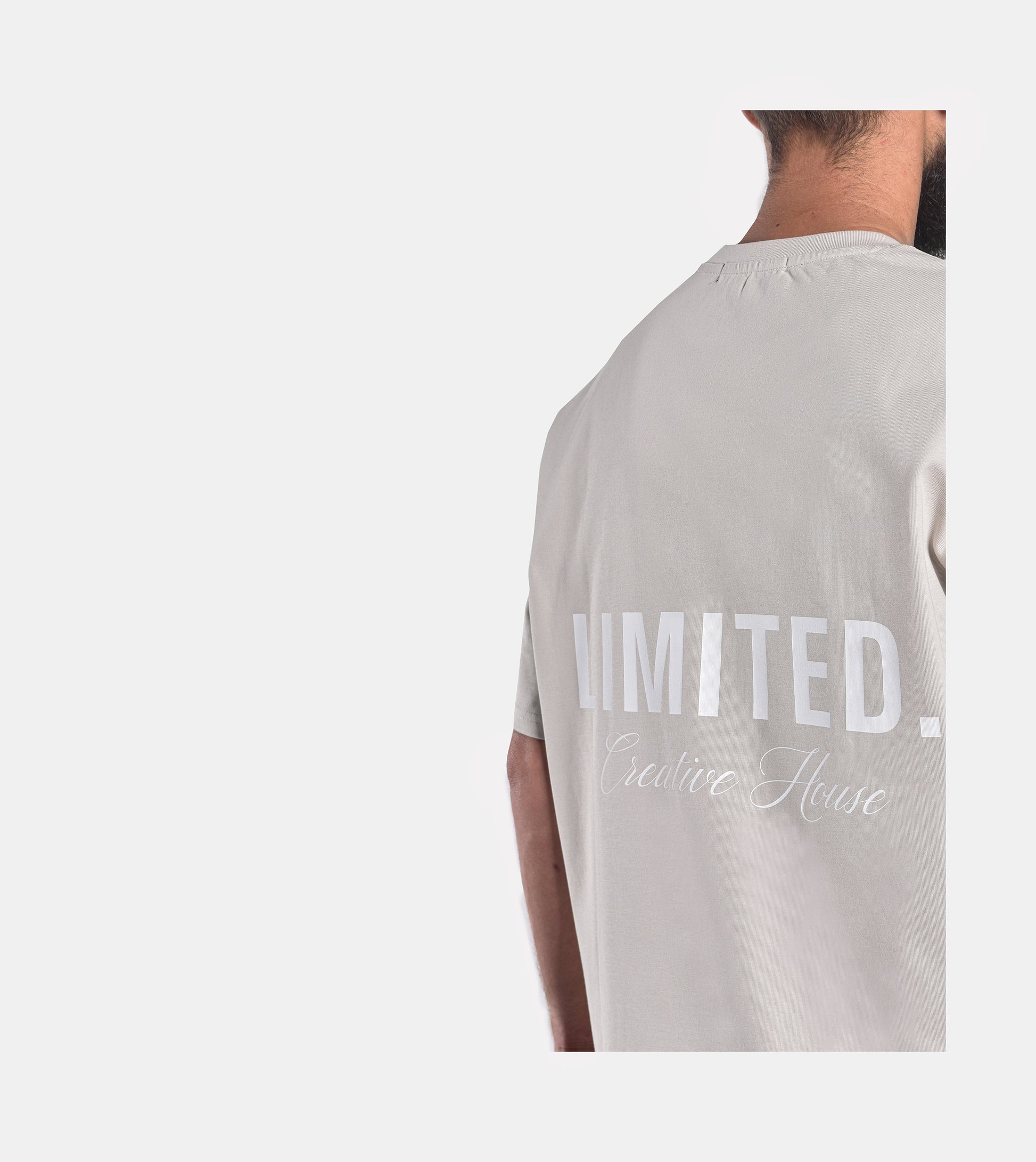 Close-up of model wearing LIMITED. Oversized mens t-shirt back view in whisper-grey with big white LIMITED. branding on the back.