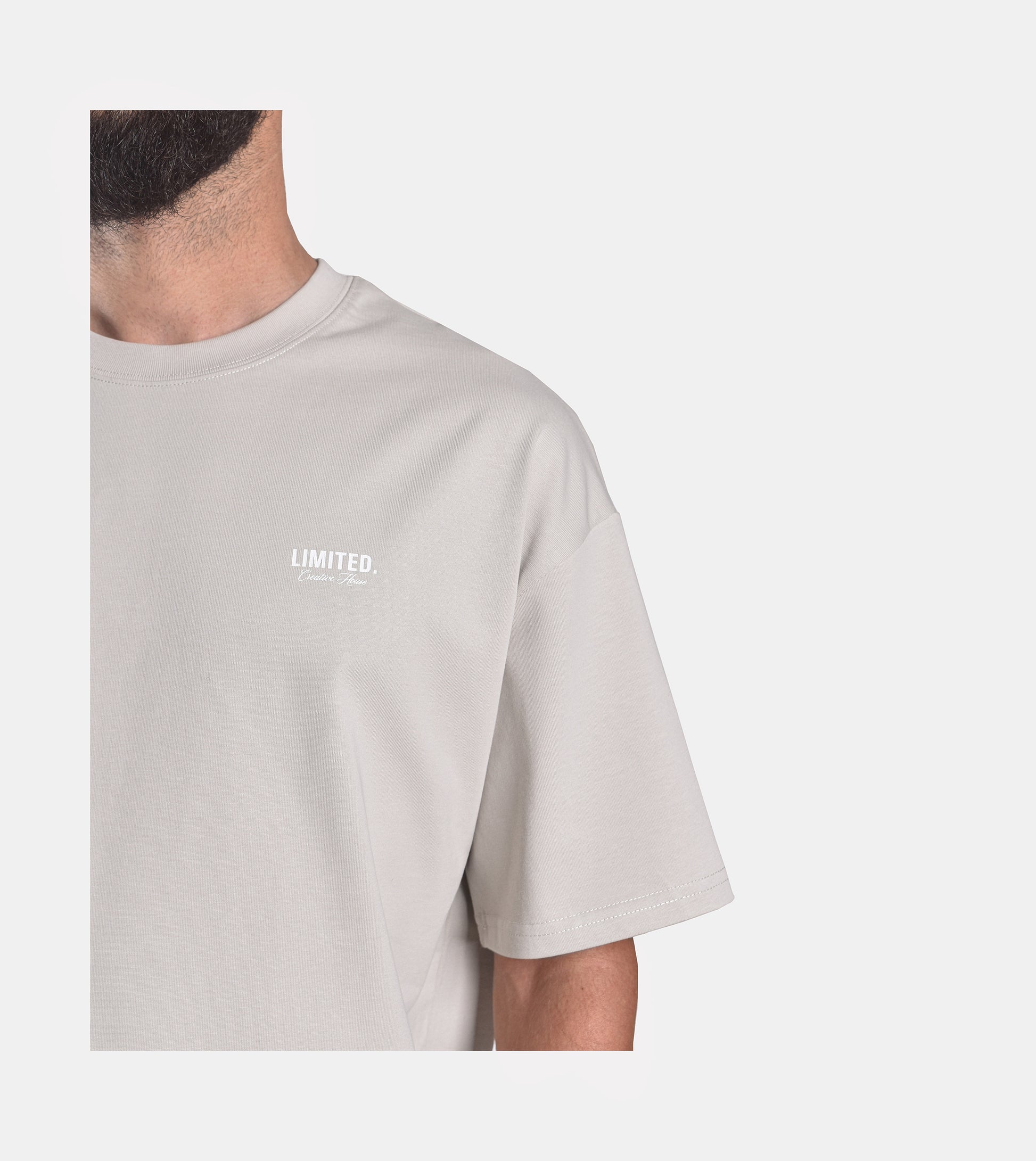 Close-up of model wearing LIMITED. Oversized mens t-shirt front view in whisper-grey with white small branding on the left chest.