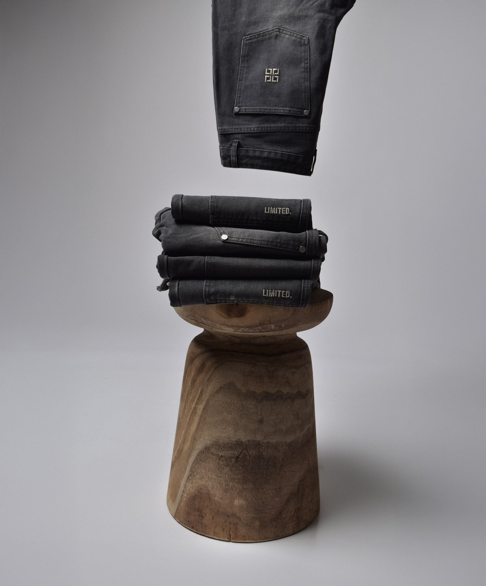 Infinity Carpenter Jeans stacked on a wooden stool
