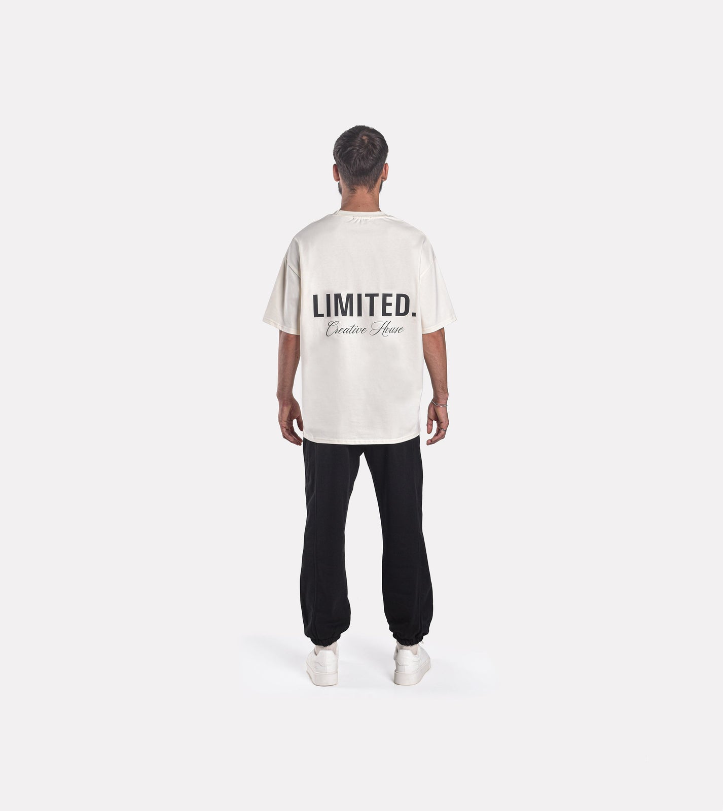 Back view of model wearing LIMITED. Oversized mens t-shirt in off-white colour with big 'LIMITED.' branding at the back