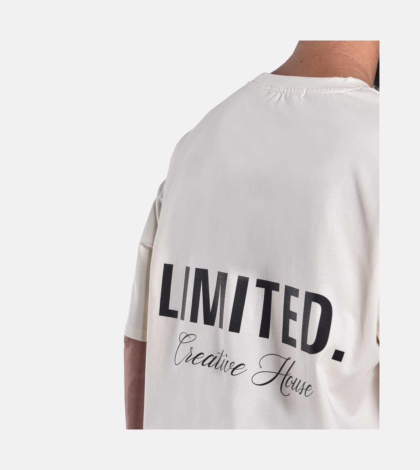Close-up of model wearing LIMITED. Oversized mens t-shirt back view in off-white colour with big 'LIMITED.' branding at the back.