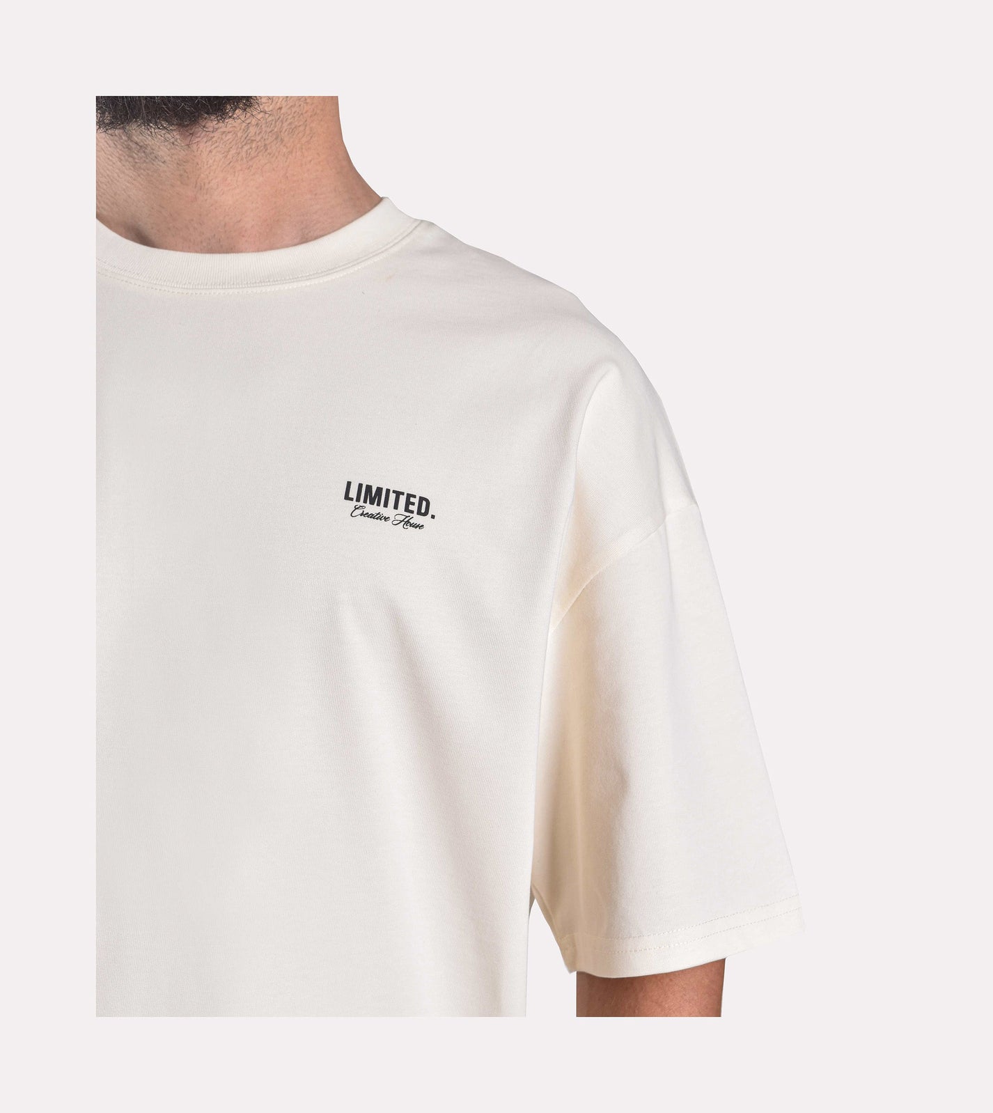 Close-up of model wearing LIMITED. Oversized mens t-shirt front view in off-white colour with small branding on the left chest.