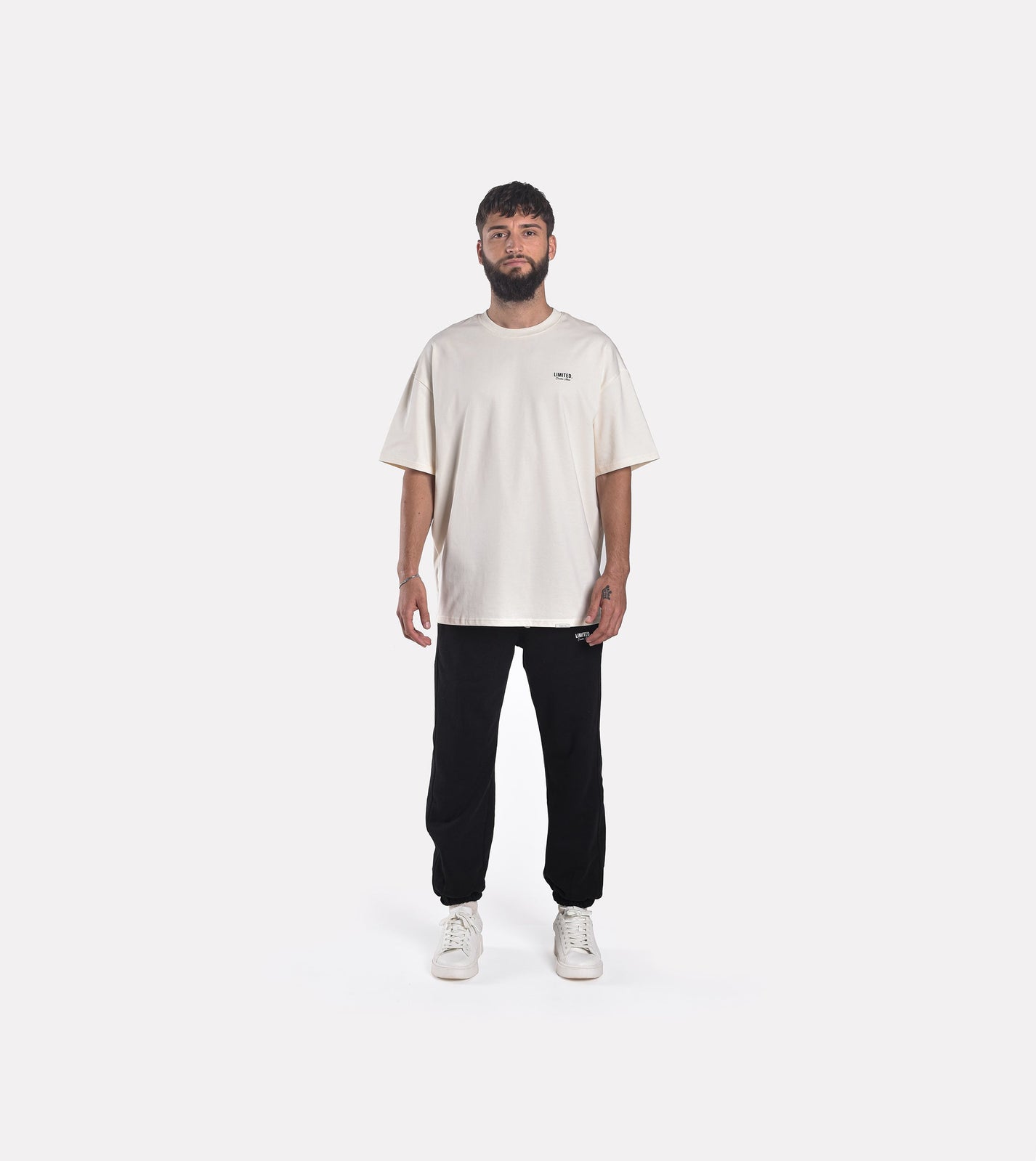 Front view model wearing LIMITED. Oversized mens t-shirt in off-white colour with small black branding on the left chest.
